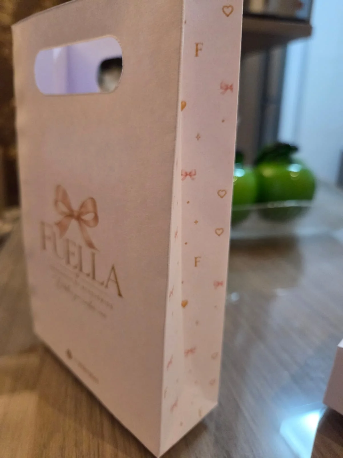 Lateral da sacola com a estampa da casa: F, coração, laço e brilho